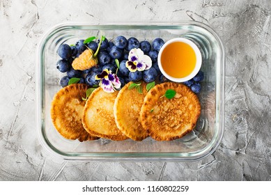 Preparation Of Food: Ready Breakfast With You: Whole-grain Fritters With Blueberries, Honey And Edible Flowers In Glass Containers. Top View