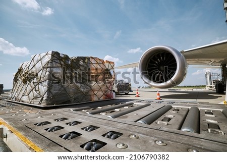 Preparation freight airplane before flight. Loading of cargo containers against jet engine of plane.