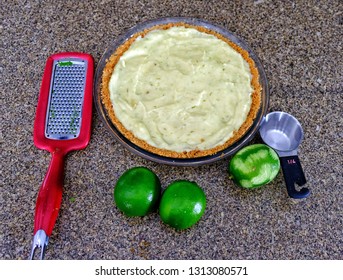 Preparation Of Key Lime Pie For Special Occasion. Pie, Grater, Limes, Measuring Cup Shotbfrom Above On Kitchen Counter