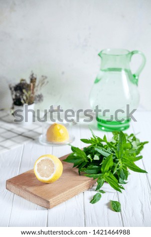 Preparation of the lemonade drink. Cutted lemon on board with fresh mint. Refreshing, cold, summer drink. Lemonade pitcher. Making traditional, healthy lemonade. Ingredients for making mojito