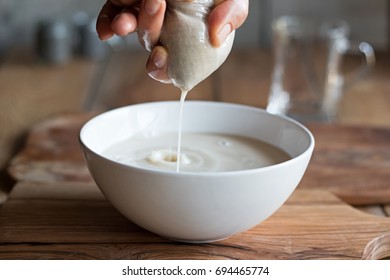 Preparation Of Nut Milk - Straining The Milk Through A Milk Bag Into A Bowl