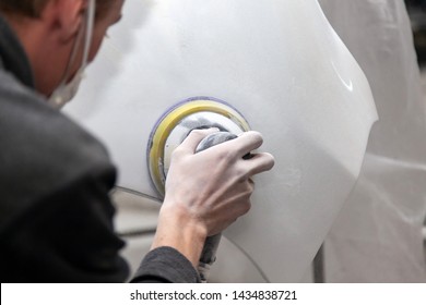 Preparation for painting a car element using sander and putty by a service technician leveling out before applying a primer after damage to a part of the body in an accident in the vehicle workshop - Powered by Shutterstock