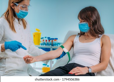 Preparation for phlebotomy procedure, female patient and medical nurse wearing protective masks