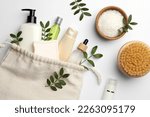 Preparation for spa. Compact toiletry bag, twigs and cosmetic products on white background, flat lay