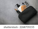 Preparation for spa. Compact toiletry bag with different cosmetic products on grey textured background, flat lay. Space for text
