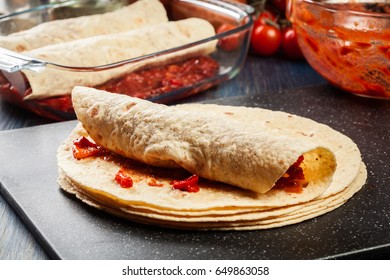Preparation traditional mexican enchiladas with chicken meat, spicy tomato sauce and cheese. Mexican cuisine.