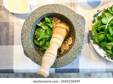 Preparation of traditional Pesto alle Genovese - with basil, olive oil, pine nuts, parmesan cheese and garlic crush in a mortar with a wooden pestle - Powered by Shutterstock