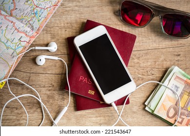 Preparation for travel, cell phone, money, passport, road map on wooden table - Powered by Shutterstock