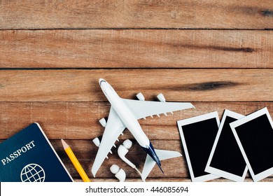 Preparation For Traveling Concept, Airplane, Photo Frame, Earphone, Pencil, Passport, On Vintage Wooden Background.