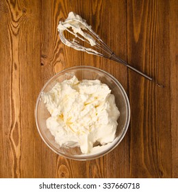 Preparation of whipped cream with a hand mixer metal on a wooden background.