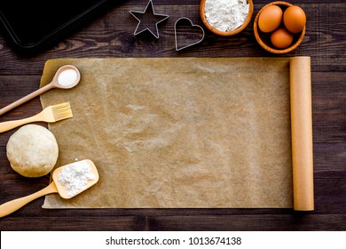 Prepare to baking. Dough ball near cookware on dark wooden background top view. Mock up with baking paper