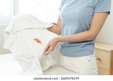 Prepare before laundry, Close-up of hands holding the white shirt dirty by strawberry sauce.