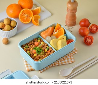 Prepare Children's School Supplies in the lunch box, with ingredients vegetables fried rice, tamagoyaki or omelet, orange, melon, and longan.  - Shutterstock ID 2183021593