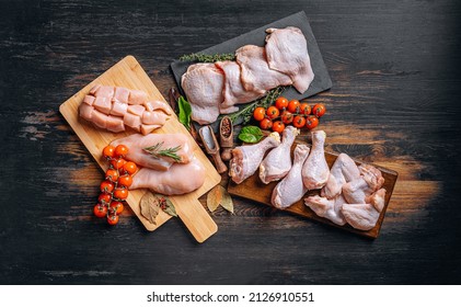 Prepared for frying, butchered various portions of raw chicken meat. Set of raw chicken fillet, thigh, wings, strips and legs on the background of the culinary table with spices and cherry tomatoes - Shutterstock ID 2126910551