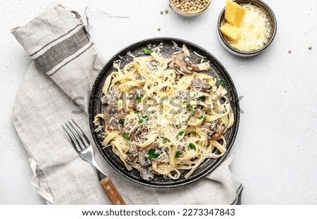Prepared pasta with mushrooms with parsley and cheese on grey table background, top view. Healthy cooking and eating. Italian food concept