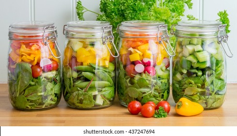 Prepared Salad In Glass Storage Jars. Four In A Line On A Wooden Kitchen Worktop. Meal Prep.