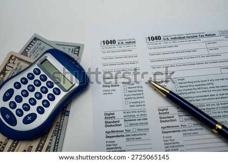 Preparing 1040 form with US dollars, glasses and calculator on wooden table for 2026 taxes