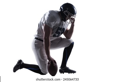 Preparing to big game. Side view of American football player holding hand on helmet while standing on knee against white background  - Powered by Shutterstock