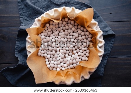 Preparing to Blind Bake a Fluted Pie Crust: Pie crust lined with parchment paper and filled with ceramic pie weights for blind baking