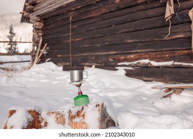 Preparing Boiling Tea Or Coffee On Primus Camping Gas Stove. Traveler Resting With A Metal Mug Of Hot Tea On A Cold Winter Day.  Adventure Begins Boiling On Gas Primus, Making Hot Drink Winter Outdoor