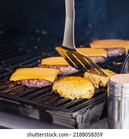 Preparing of Cheeseburgers on outdoor grill, selective focus. Food cooking outdoors, backyard barbecue concept