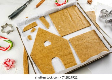 Preparing for Christmas, making a gingerbread house. Baking tray with dough in the form of house details, ornaments in the frame. 