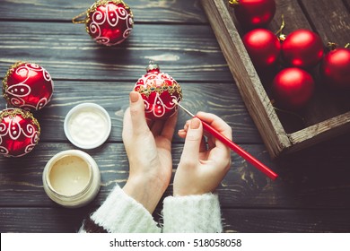 Preparing for Christmas. Woman paints the festive decor on vintage wooden background. Handmade decorations. The cozy stuff for the house

 - Powered by Shutterstock