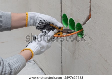 Preparing the electrical cabling. The tradesman uses pliers and a cutting knife to prepare the wiring.