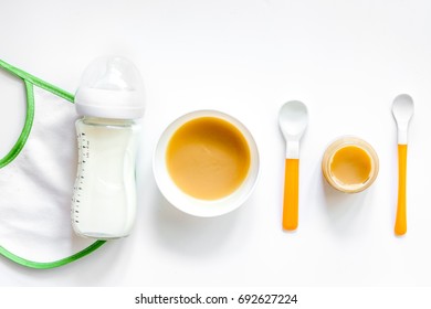 Preparing To Feed Baby. Puree, Spoon, Nipple, Bottle And Bib On White Background Top View Copyspace