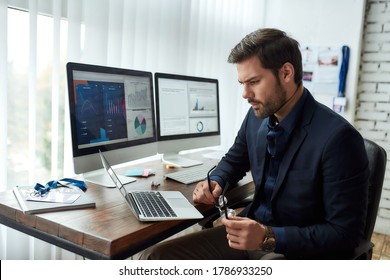 Preparing financial report  Young focused businessman financial analyst sitting at his workplace in the office   working laptop  Analyzing statistical data  Focus man  Business  finance