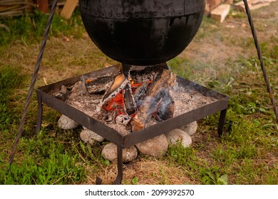 Preparing food in hanging black pot over open fire at historical festival - close up view. Outdoor cooking, hiking, tourism, travelling, camping concept