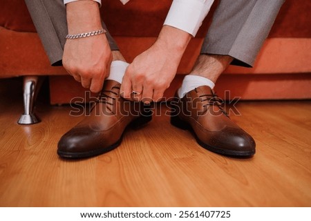 Preparing for a Formal Event: A Man Tying His Brown Dress Shoes.