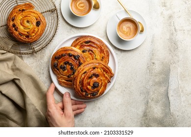 Preparing french or continental breakfast with espresso coffee and croissant. Pain aux raisins, also called escargot or pain russe, is a spiral pastry with custard cream and raisin.