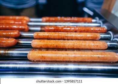 Preparing The French Hot Dog. Spinning Sausages On The Grill