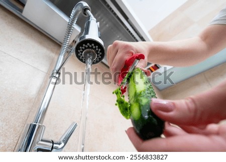 Preparing a fresh cucumber under running water for a healthy and delicious meal.