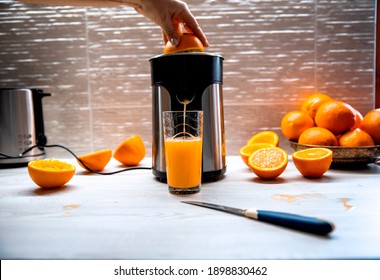 Preparing Fresh Orange Juice Using Kitchen Squeezing Appliance. 