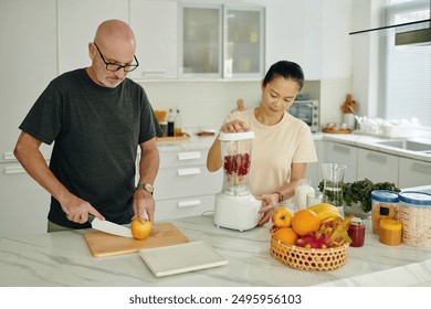 Preparing Fruit Smoothie and Slicing Orange in Modern Kitchen - Powered by Shutterstock