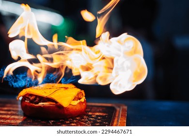 preparing a gourmet cheeseburger on restaurant kitchen with fire - Powered by Shutterstock