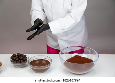 Preparing Handmade Candies Or Truffles On Backdrop Of Ingredients For Making Chocolate - Raw Cocoa Powder, Melted Dark Chocolate And Almonds. Confectionary Manufacturing Small Business Idea Concept