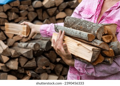 Preparing for the heating season with wood heating. Firewood in the hands of woman.