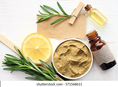 Preparing Homemade Skincare Mask With Natural Ingredients: Bentonite Clay, Rosemary, Lemon Slice, Essential Oil, Note For Recipe