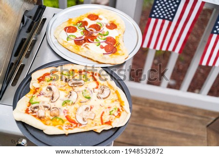 Preparing individual grilled pizzas on an outdoor gas grill.
