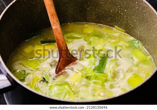 Preparing\
leek soup in cooking pot with wooden\
spatula