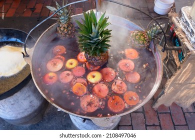 Preparing mulled wine at outdoor stall. Pineapples boiling in wine in the cauldron.
