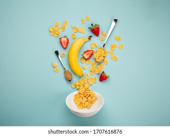 Preparing quick healthy breakfast in the morning: adding cereals, ripe banana, fresh strawberry into white bowl. Ingredients for making breakfast with granola and fruits on blue background, top view - Powered by Shutterstock