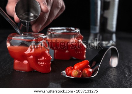 Preparing shots of bloody Mary in a glass in the shape of a skull.