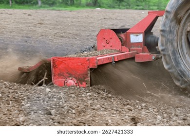 preparing soil for planting using tractor with rotary tiller cultivator.