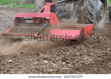 preparing soil for planting using tractor with rotary tiller cultivator.