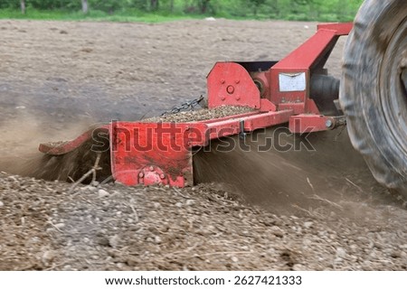 preparing soil for planting using tractor with rotary tiller cultivator.