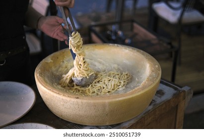 Preparing spaghetti in a wheel of Grana Padano cheese. A ladle is used to roll up the pasta. - Powered by Shutterstock